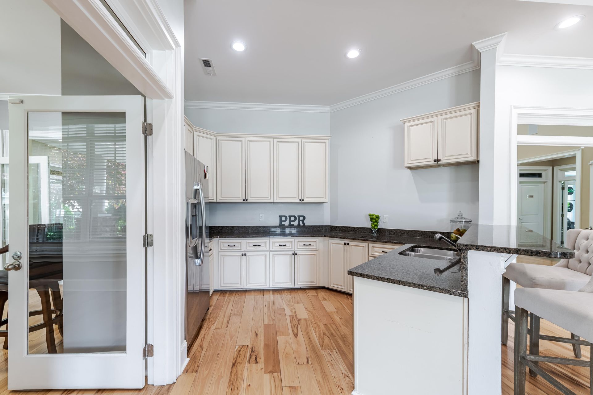 Kitchen with white cabinets, dark countertops, and hardwood floors at Plantation at Pleasant Ridge in Greensboro, NC.