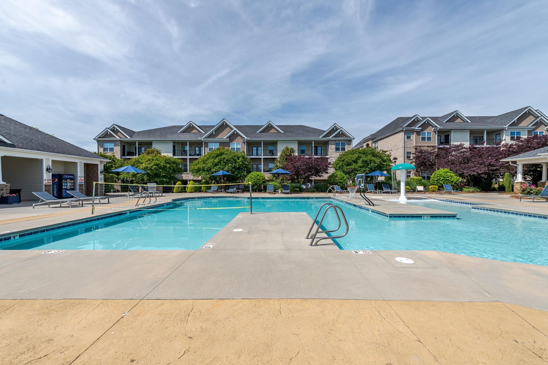 Swimming pool in front of apartment buildings on a sunny day at Plantation at Pleasant Ridge in Greensboro, NC.