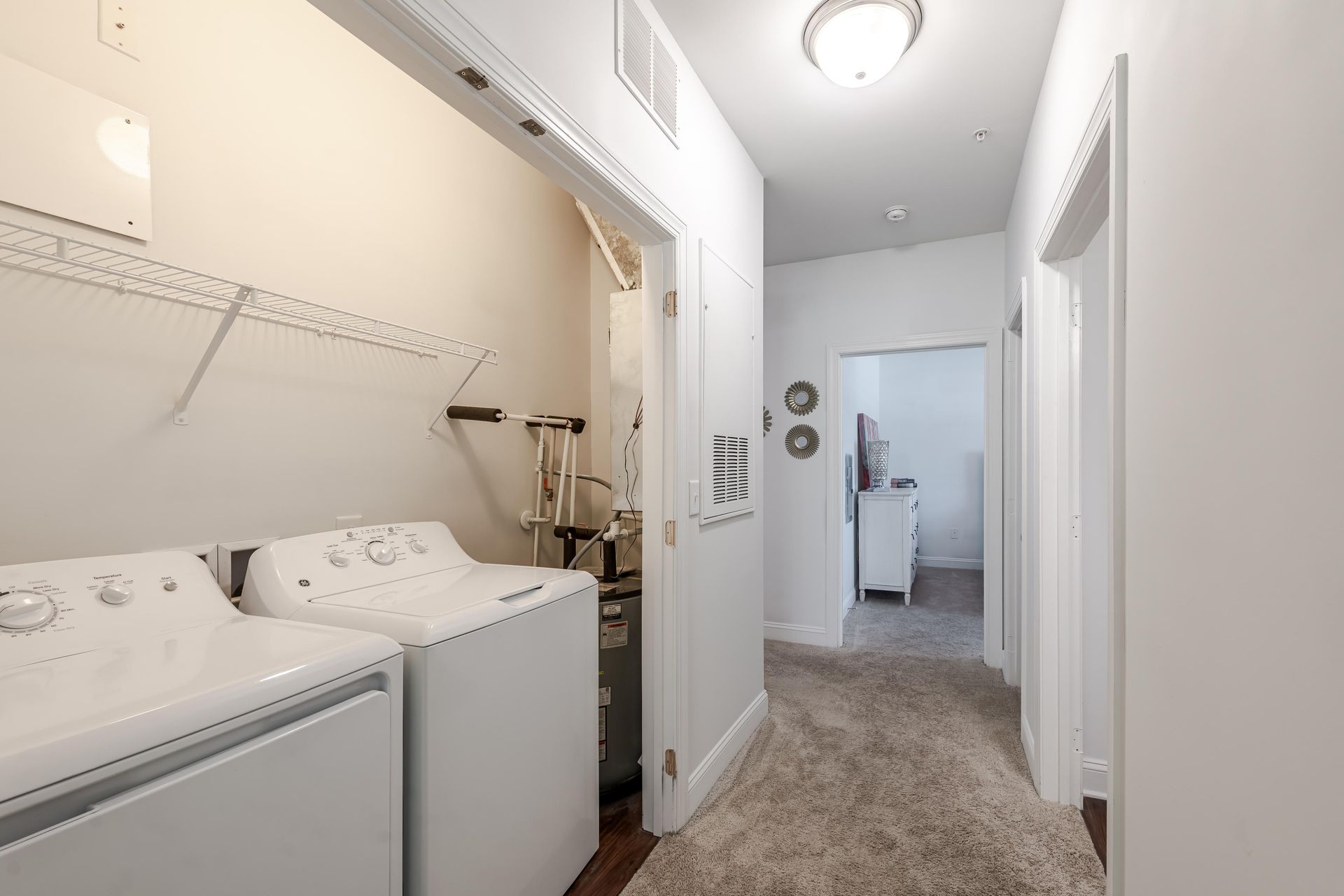 Laundry room with washer, dryer, hallway with door to another room at Plantation at Pleasant Ridge in Greensboro, NC.
