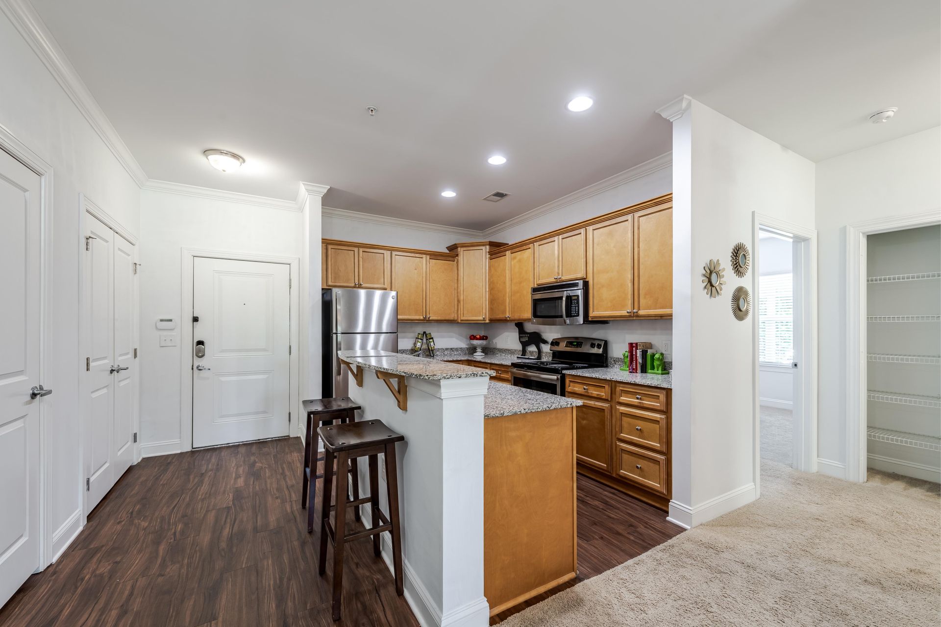Kitchen with wood cabinets, stainless steel appliances, and a breakfast bar with stools at Plantation at Pleasant Ridge in Greensboro, NC.