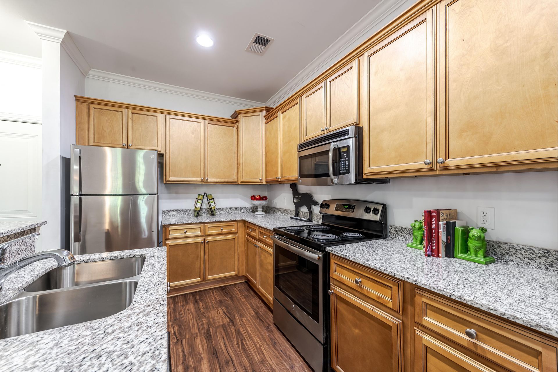 Kitchen with stainless steel appliances, light wood cabinets, and granite countertops at Plantation at Pleasant Ridge in Greensboro, NC.