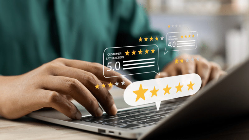 Person typing on laptop; floating stars and rating bubbles reflect online customer reviews.