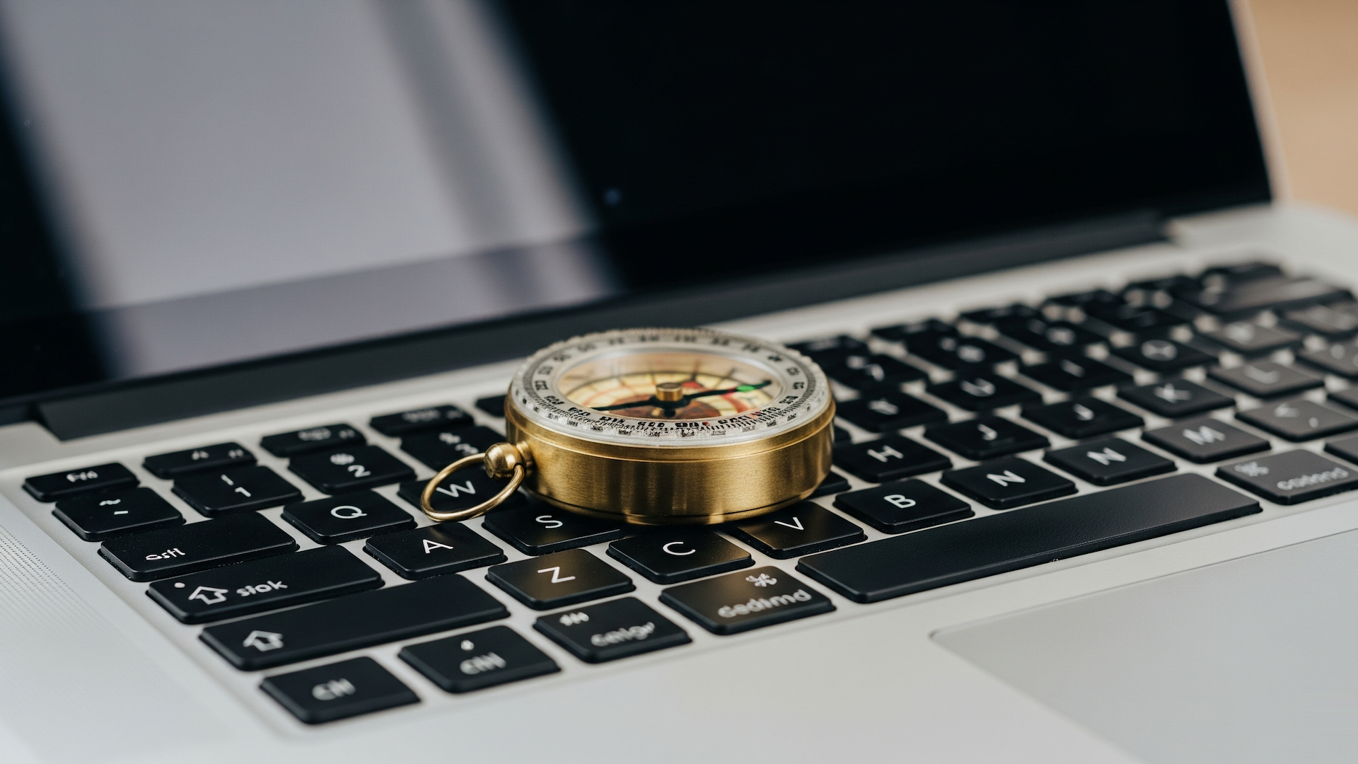 Compass on a laptop keyboard, suggesting navigation or direction in a digital context.