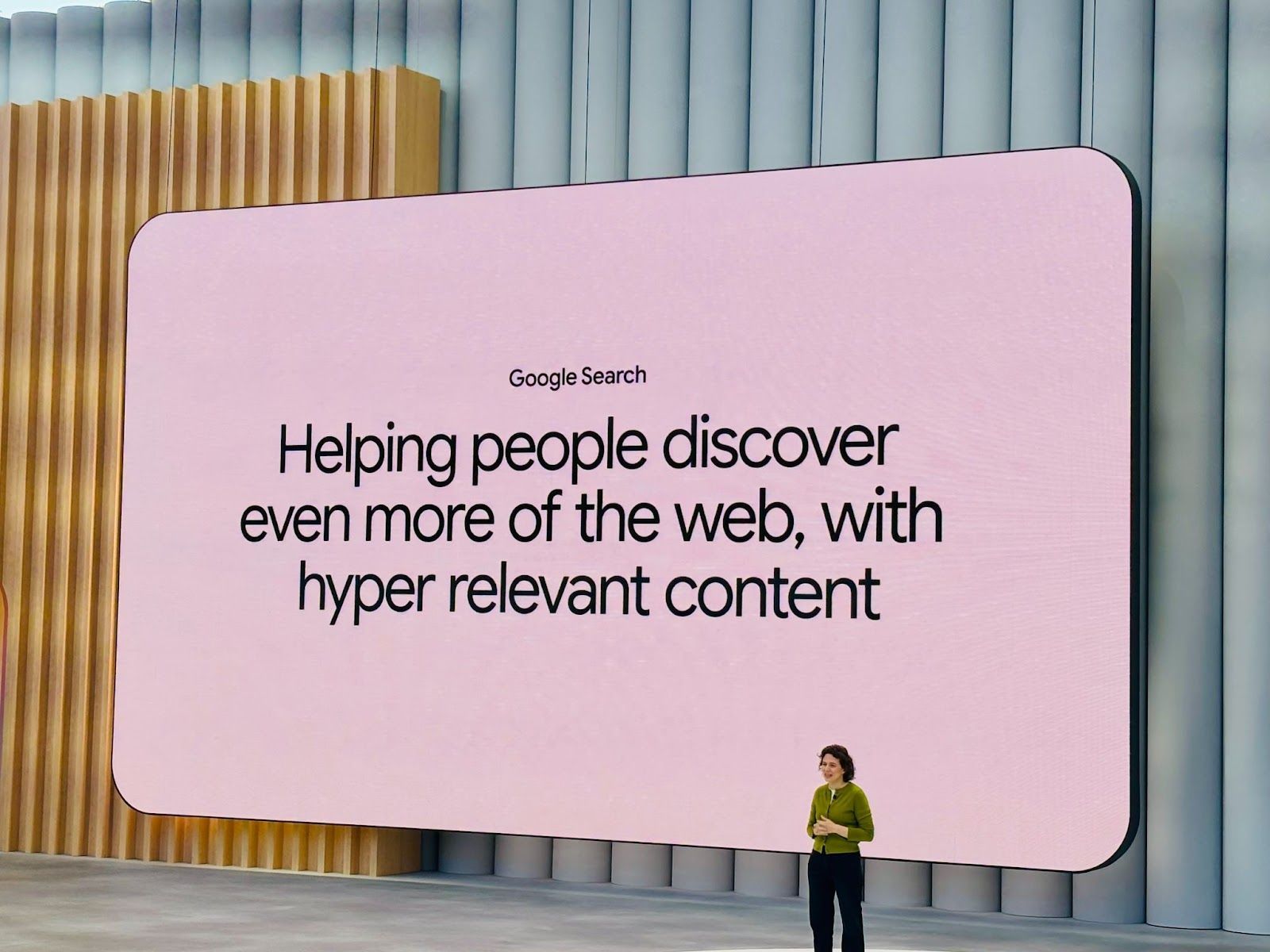 A woman stands before a large screen that reads 