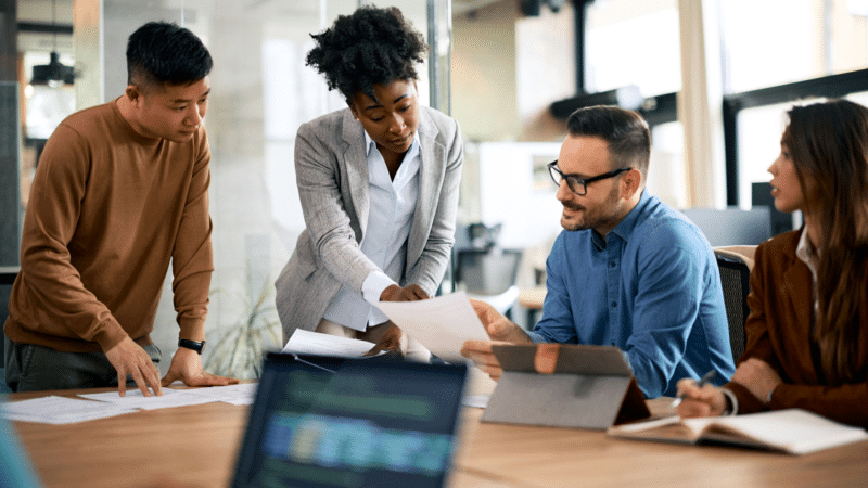 A diverse group of businesspeople reviewing documents at a conference table in a modern office.
