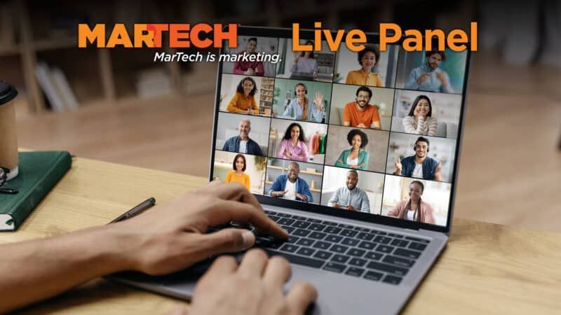 Laptop displaying a live panel video conference with diverse participants; person's hands typing on keyboard.