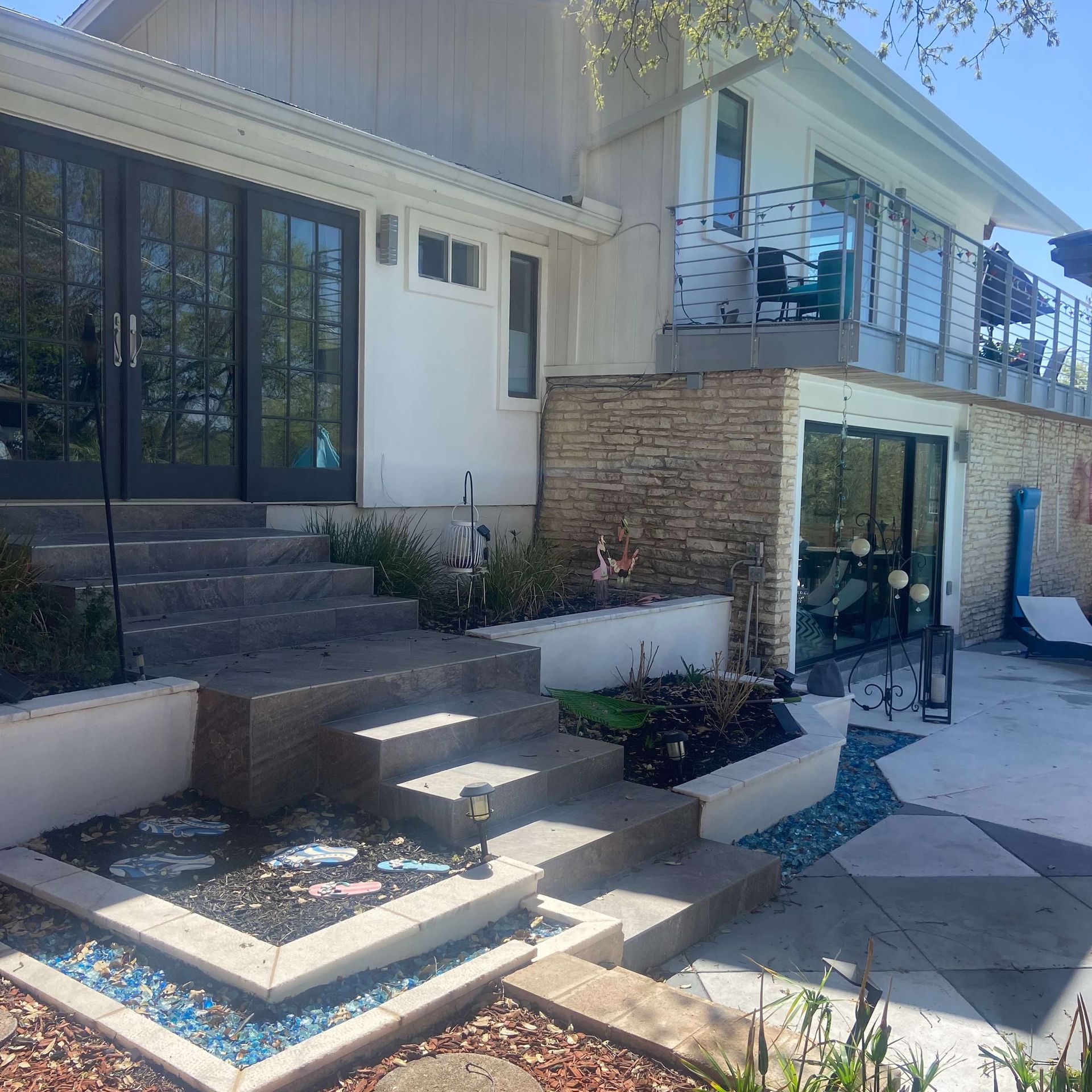 House exterior with steps, glass doors, a balcony, and a small pool area.