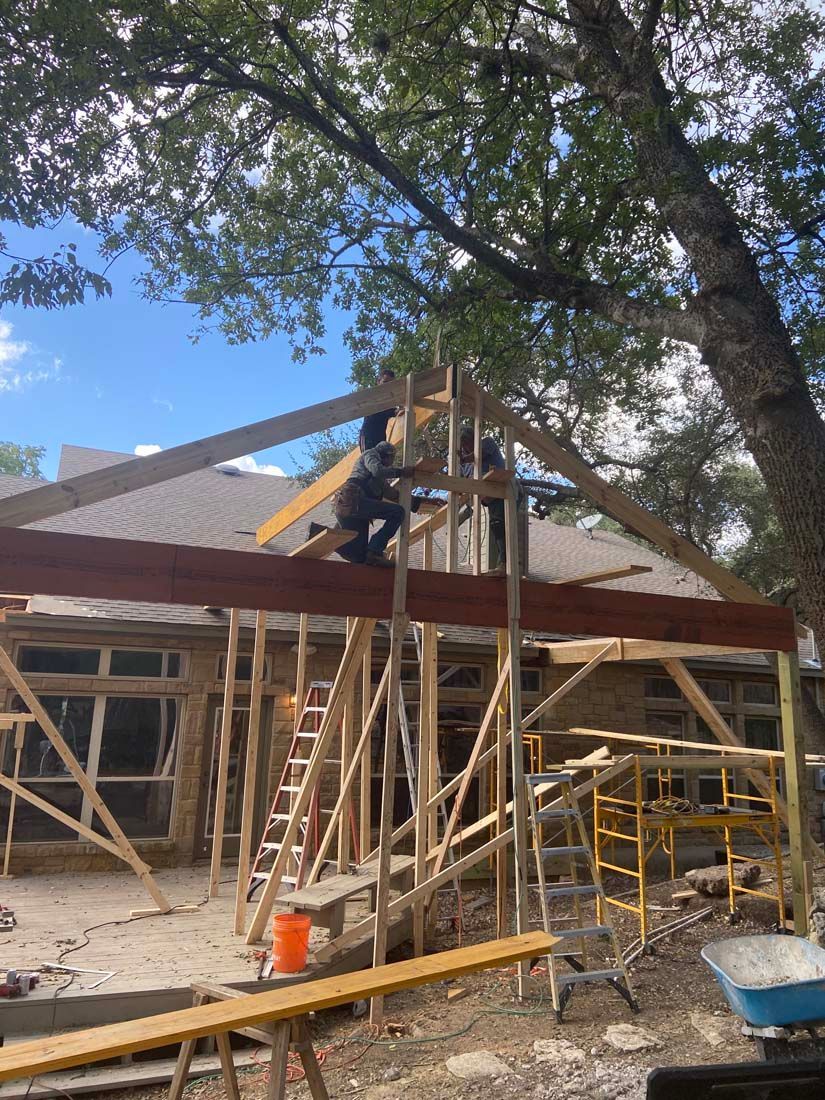 Construction workers on roof framing a house, wooden scaffolding and blue sky.