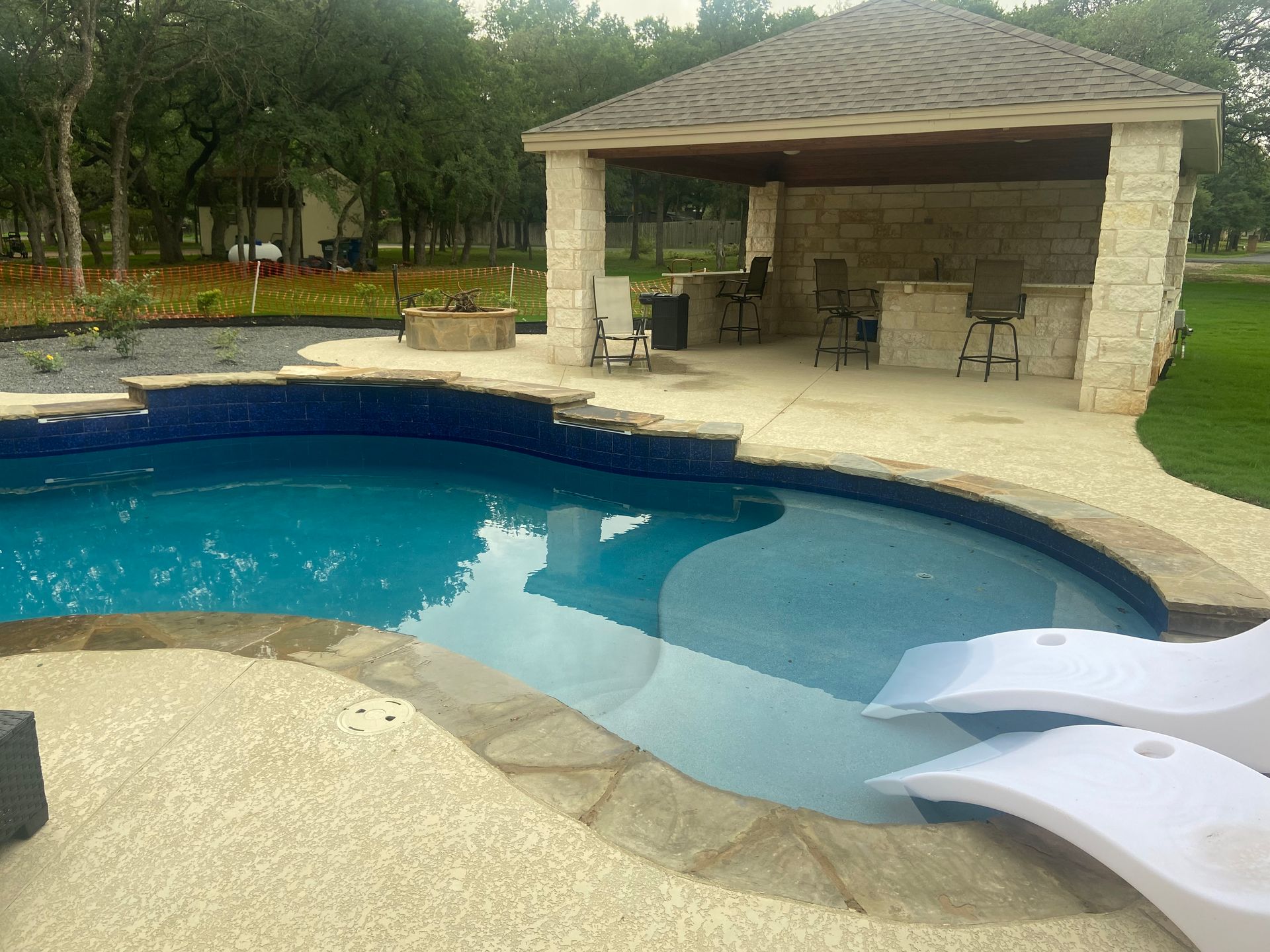 Pool with a shaded bar area. Lounge chairs on the pool deck.