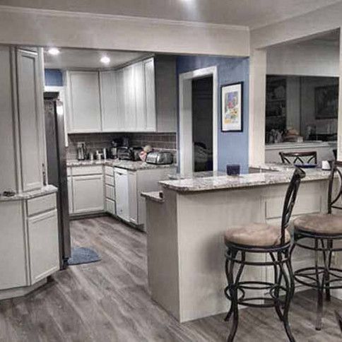Kitchen with white cabinets, breakfast bar with stools, and stainless steel appliances.