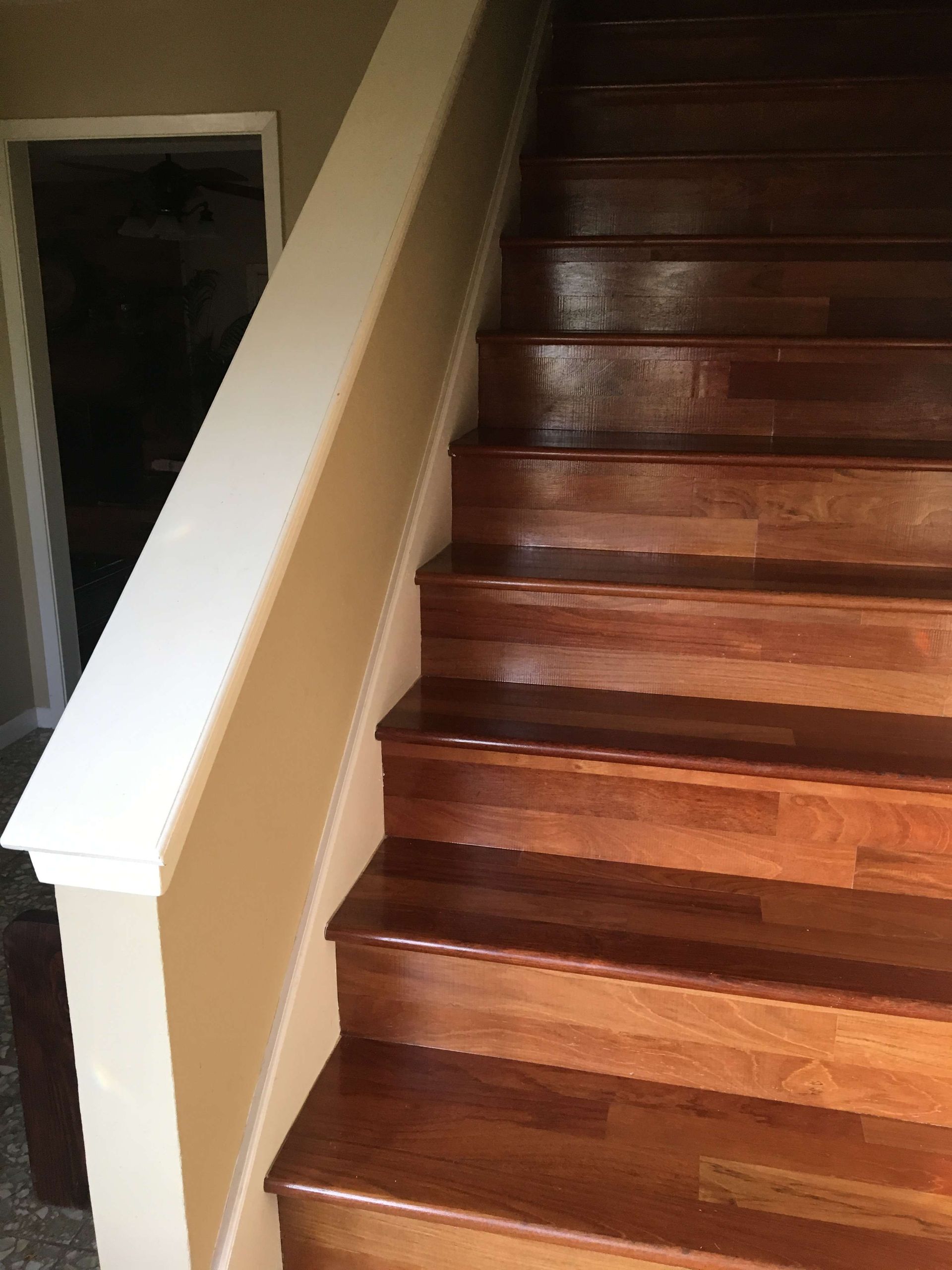 Wooden staircase with white railing and wall, leading upwards.