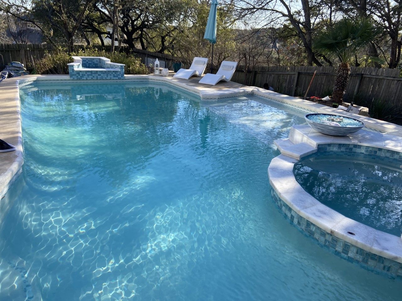 Swimming pool with turquoise water, jacuzzi, lounge chairs, and a fire pit.