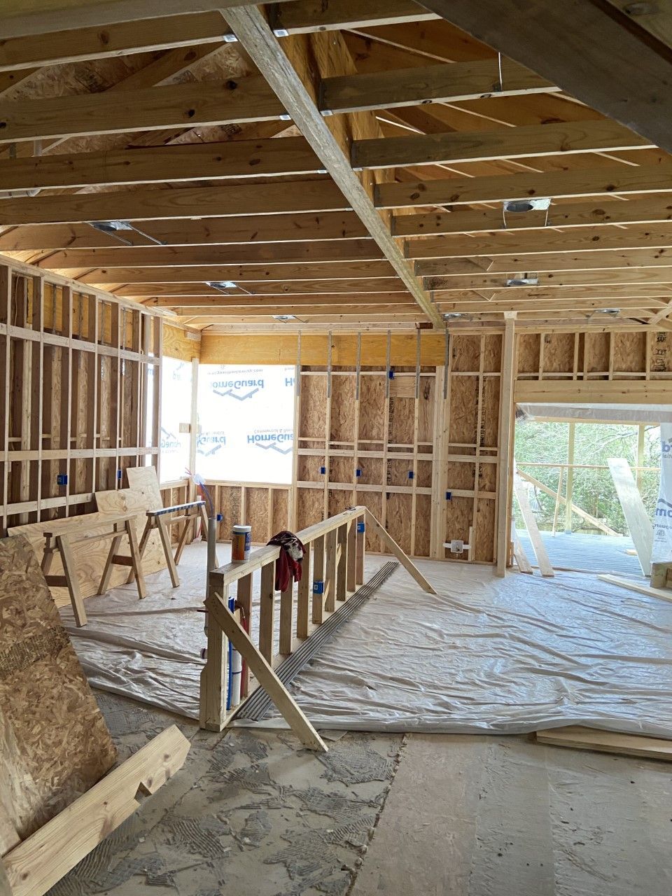 Interior of a building under construction with wooden framing, a window, and a sliding glass door.