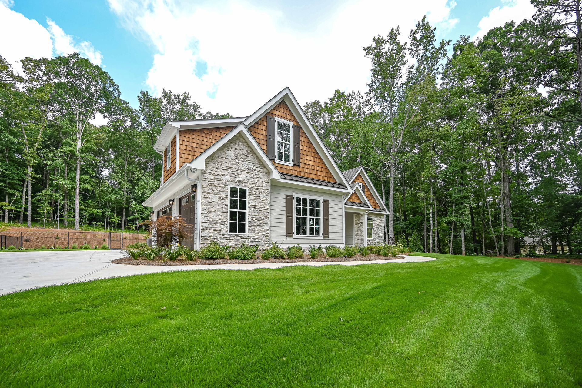 A large house with a lot of grass in front of it is surrounded by trees.