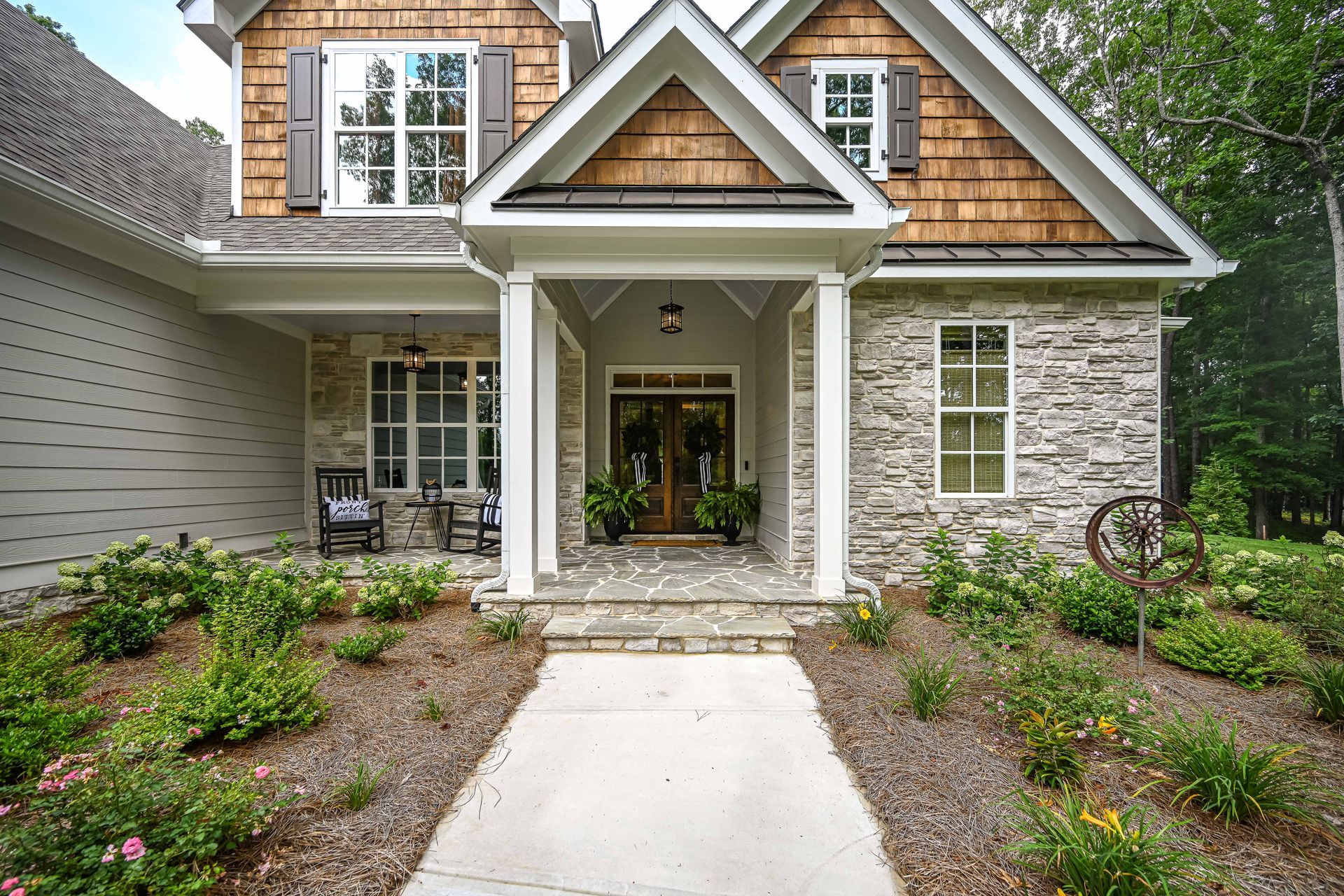 The front of a house with a large porch and a walkway leading to it.