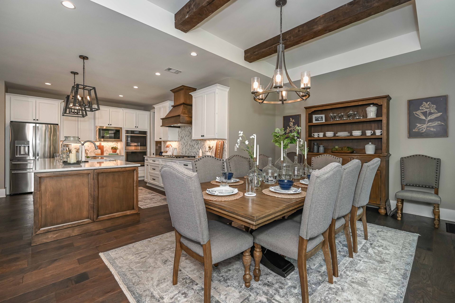 A dining room with a table and chairs and a kitchen in the background.