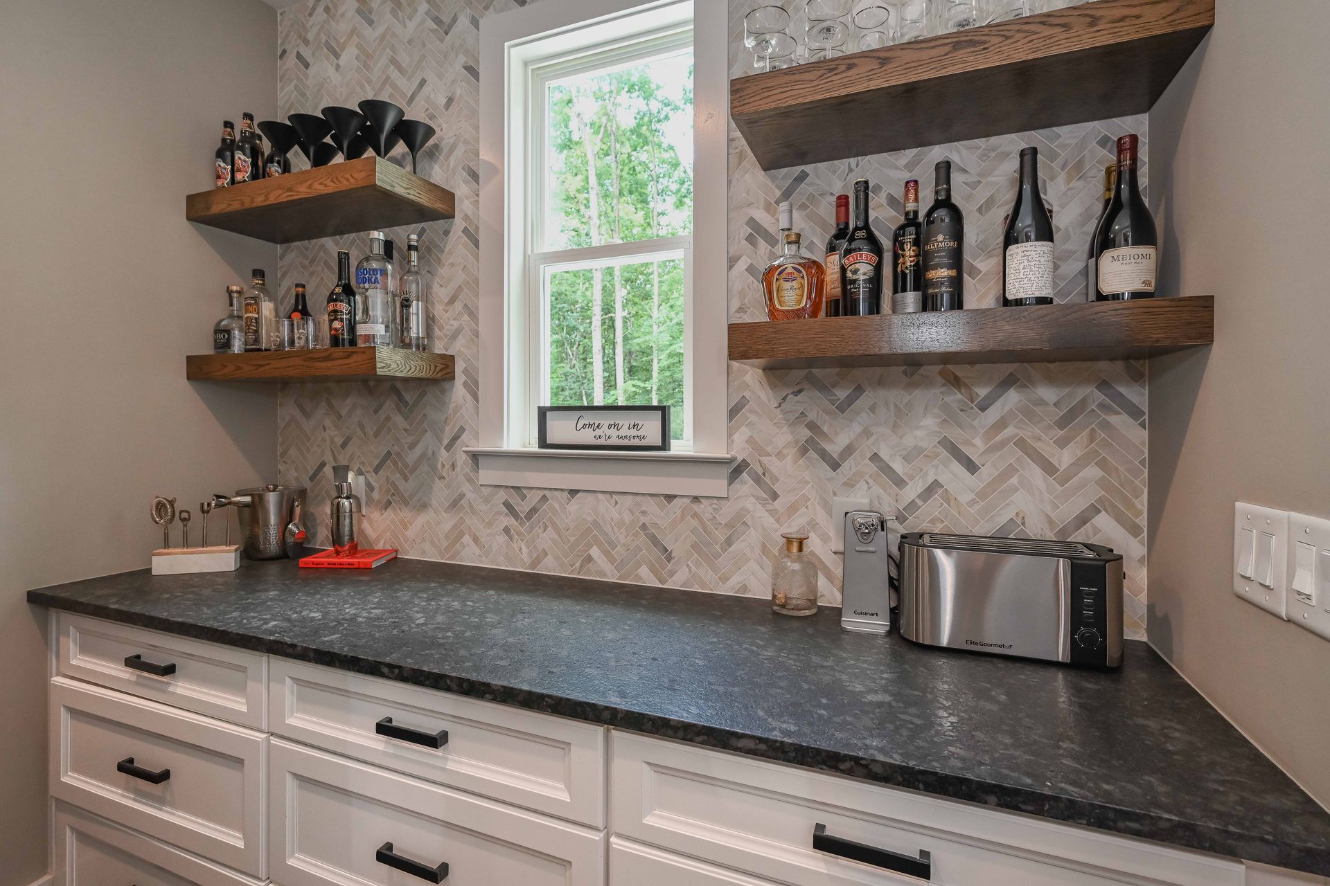 There are many bottles of alcohol on the shelves in this kitchen.