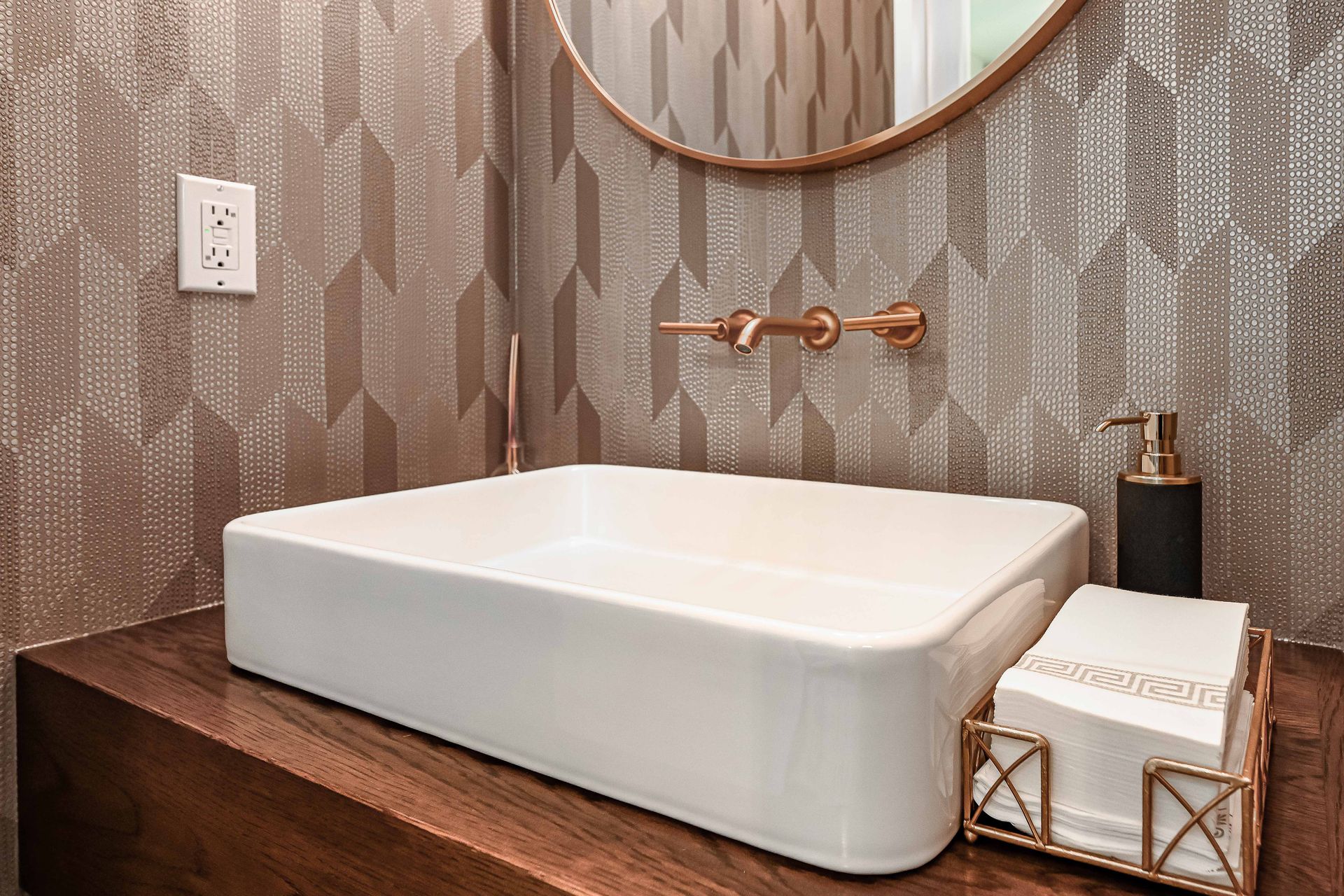 A bathroom with a sink , mirror and soap dispenser.