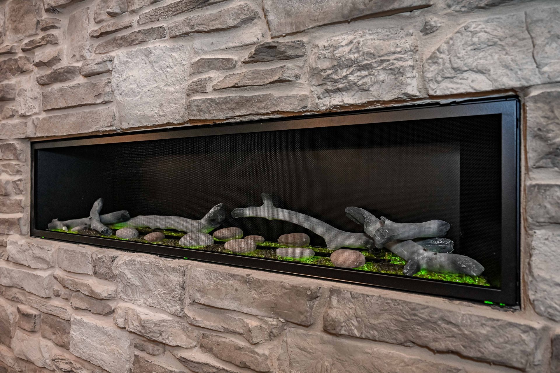 A fireplace is built into a stone wall and has a lot of rocks in it.