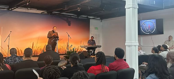 A man is giving a speech in front of a crowd of people in a church.