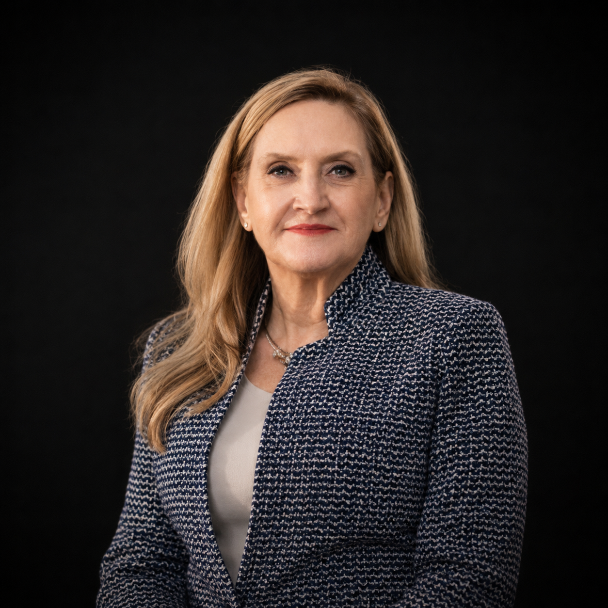 Portrait of a woman in a navy blazer against a black background