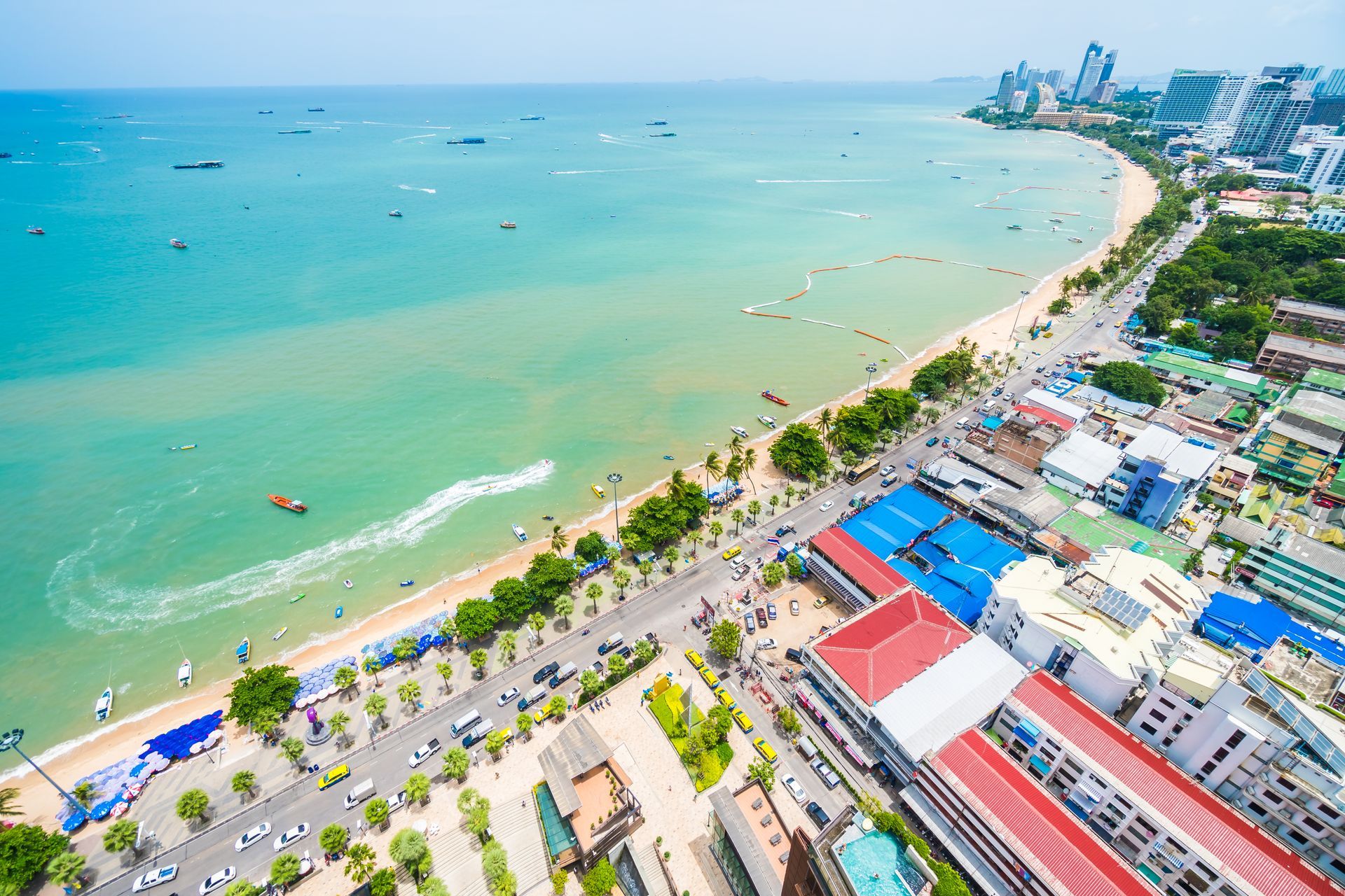 Aerial view of Pattaya Beach, Thailand, with buildings, a beach, and turquoise water.