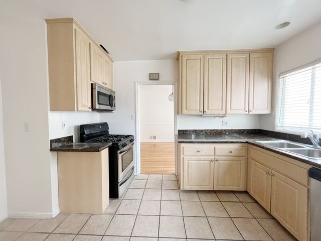 An empty kitchen with wooden cabinets and stainless steel appliances