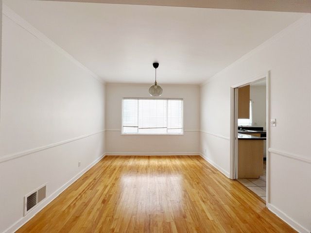 An empty room with hardwood floors and white walls