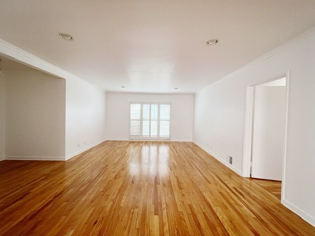 An empty room with hardwood floors and white walls