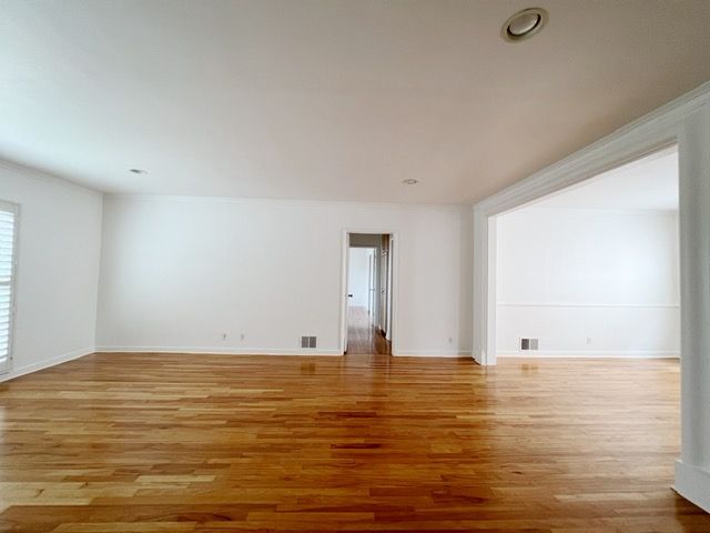An empty living room with hardwood floors and white walls
