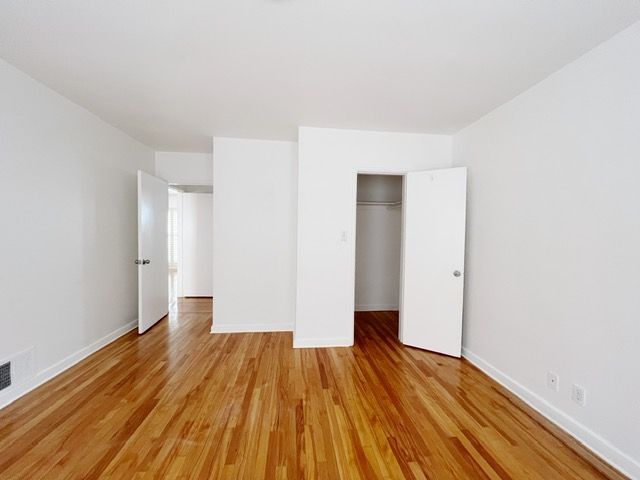 An empty room with hardwood floors and white walls