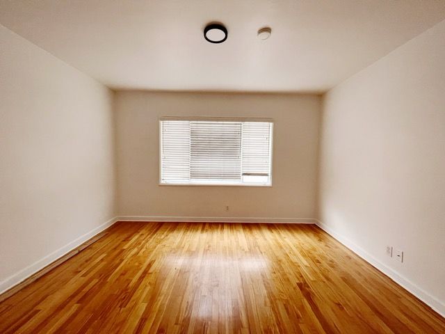An empty room with hardwood floors and a window