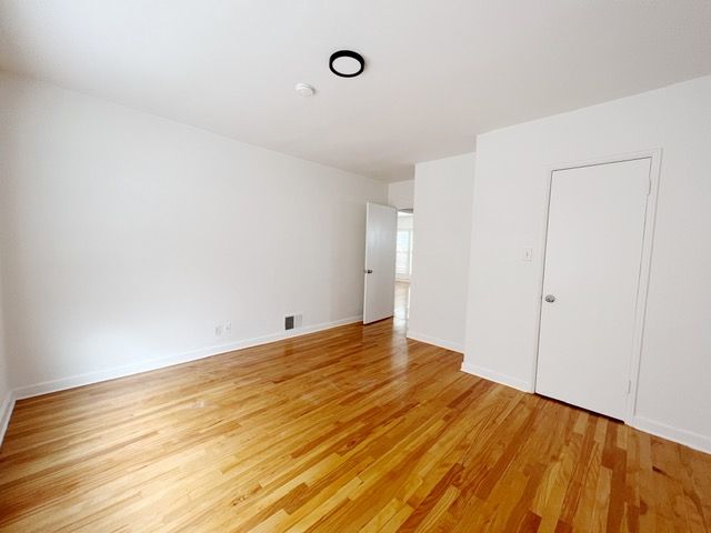 An empty room with hardwood floors and white walls