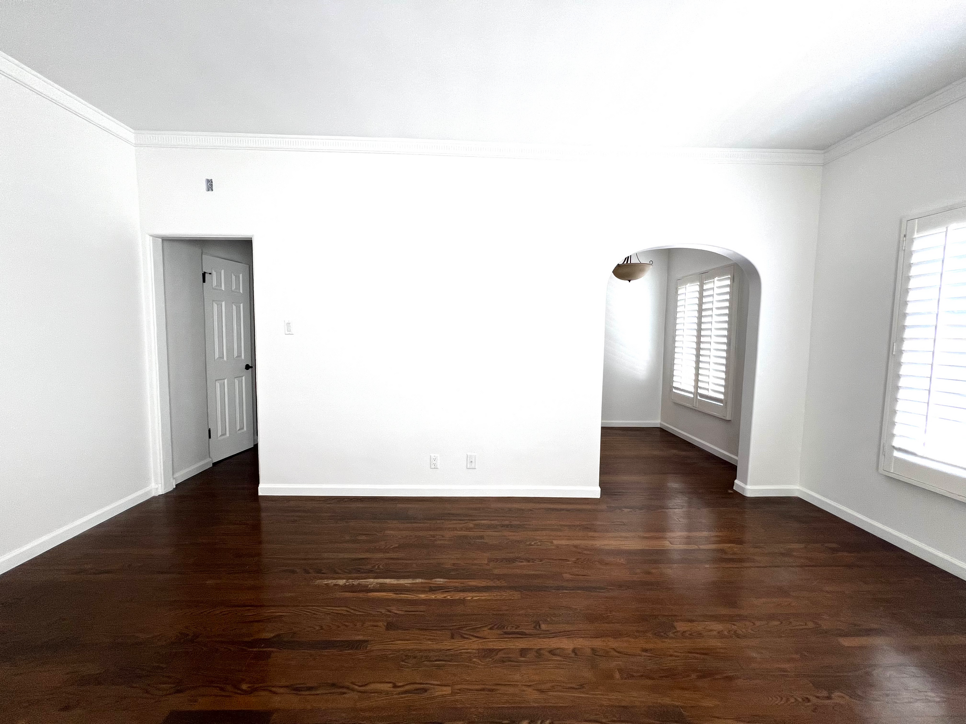 An empty living room with hardwood floors and white walls