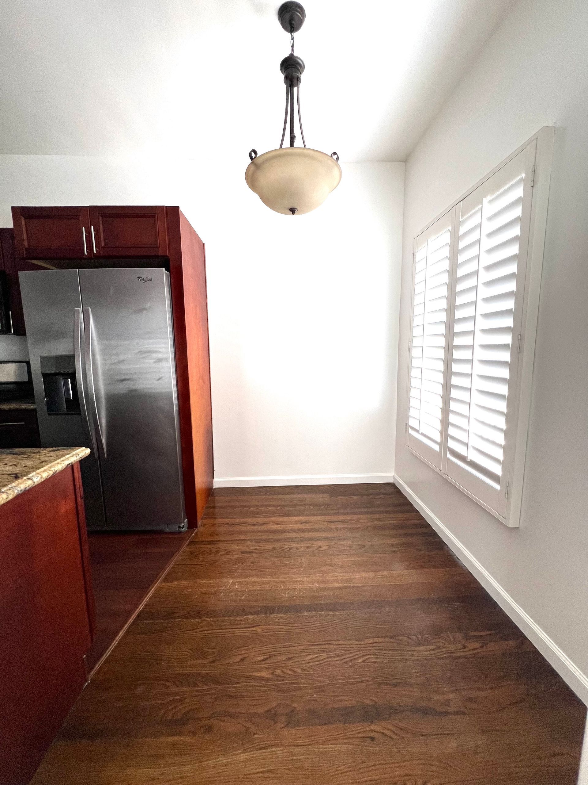 A kitchen with a refrigerator and shutters on the windows