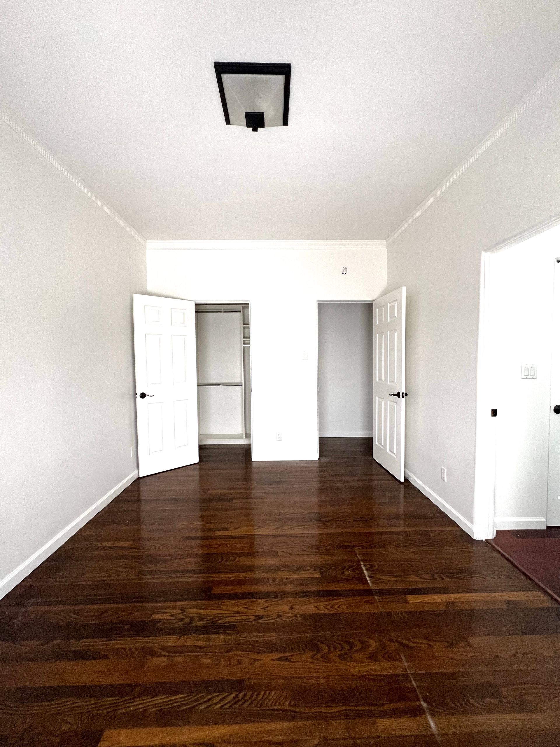 An empty room with hardwood floors and white walls