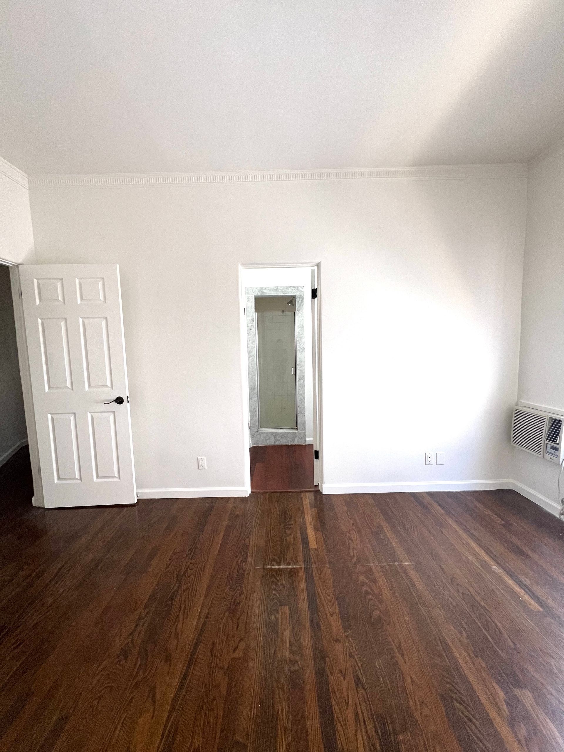 An empty living room with hardwood floors and white walls.