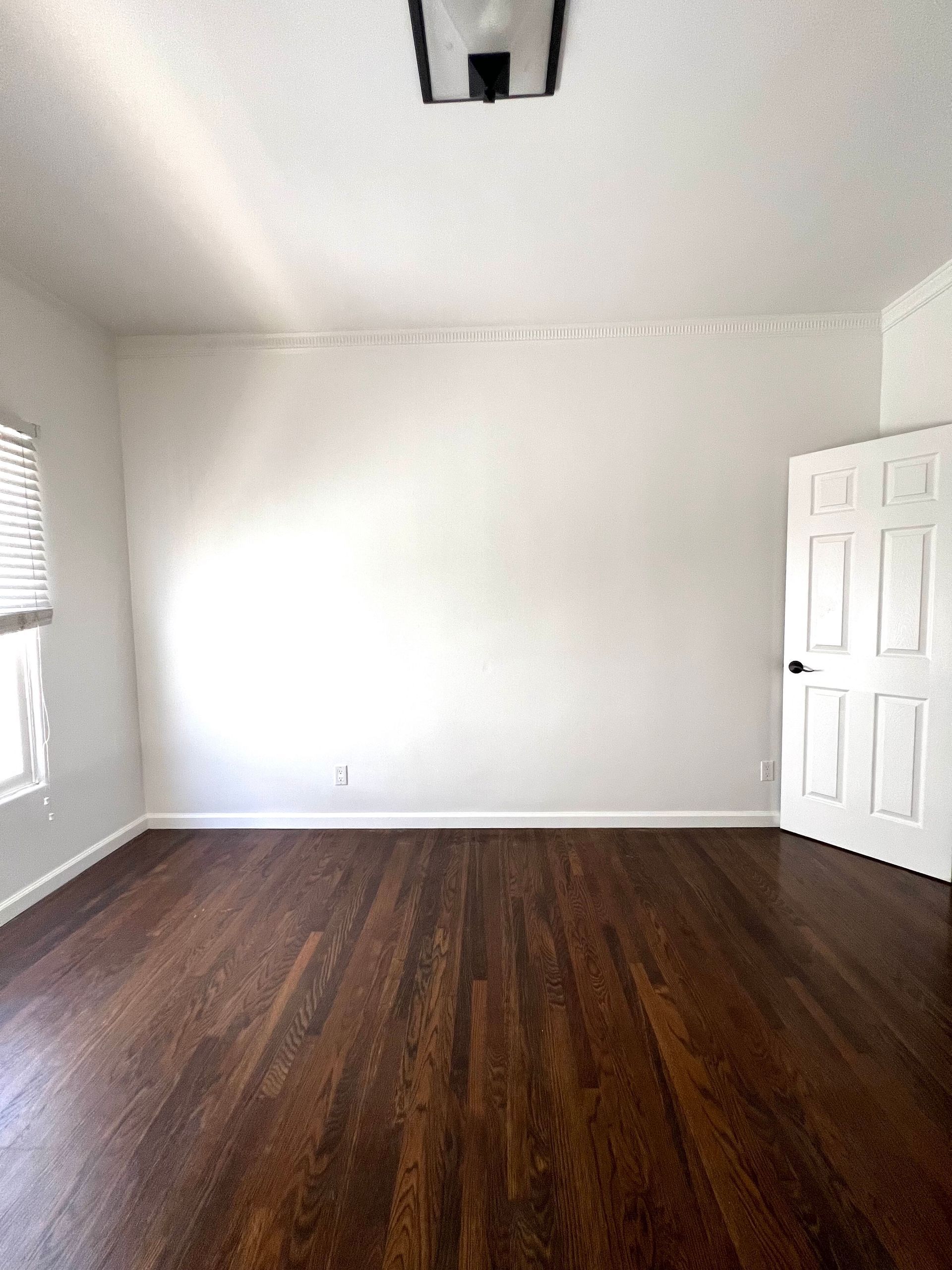 An empty room with hardwood floors and white walls.