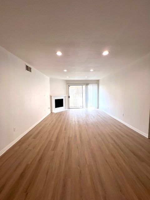 An empty living room with hardwood floors and a fireplace.