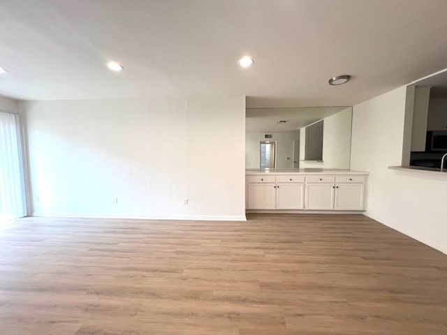 An empty living room with hardwood floors and white walls.
