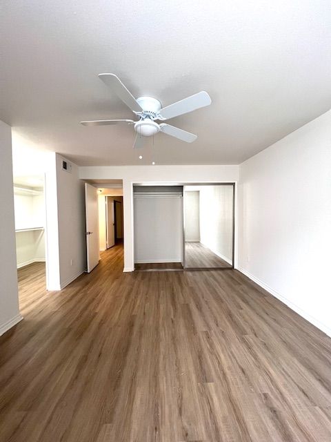An empty living room with hardwood floors and a ceiling fan.