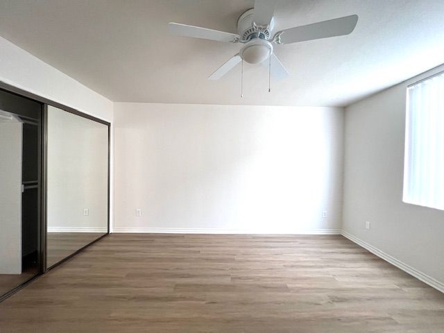 An empty room with a ceiling fan and a mirror.