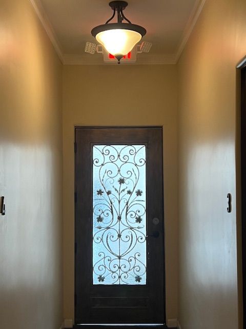 A hallway with a wrought iron door and a ceiling light
