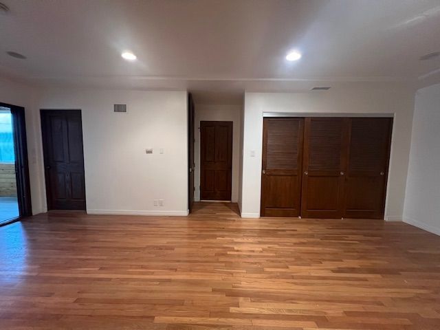 An empty living room with hardwood floors and sliding glass doors.