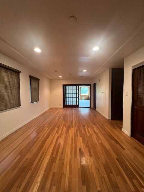An empty living room with hardwood floors and white walls