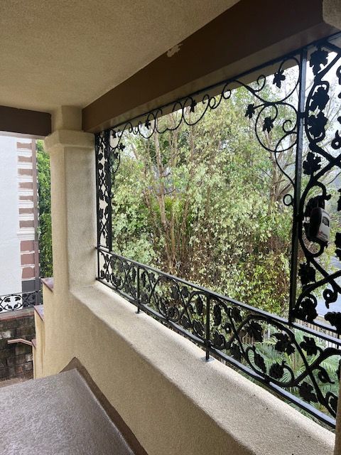 A balcony with a wrought iron railing and a view of trees