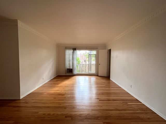 An empty living room with hardwood floors and white walls.