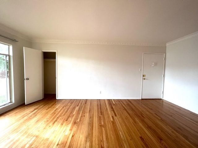An empty living room with hardwood floors and white walls.