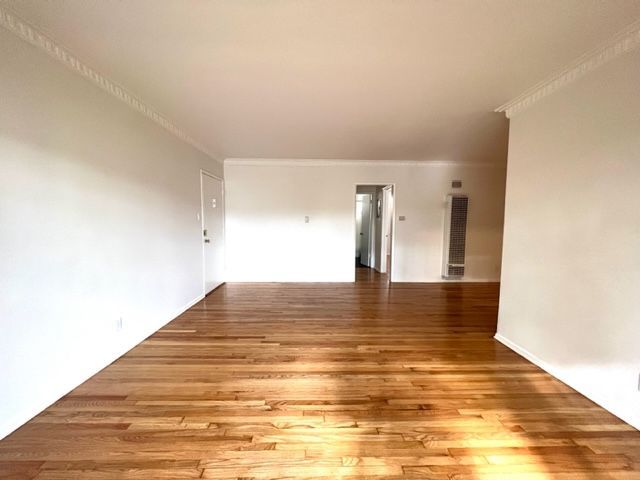 An empty living room with hardwood floors and white walls