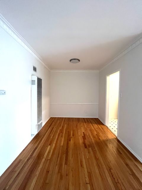 An empty living room with hardwood floors and white walls.